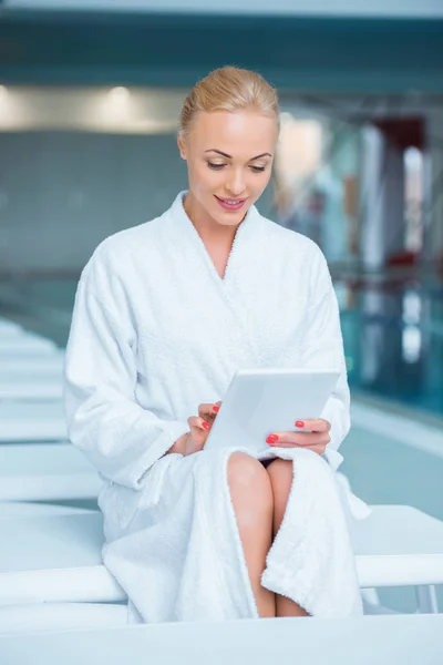 Mulher bonita sentada em roupão de banho com tablet digital — Fotografia de Stock