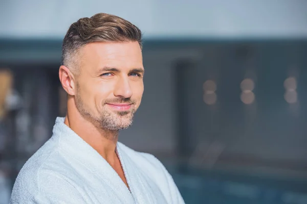 Primer plano del hombre guapo sonriendo en albornoz blanco - foto de stock