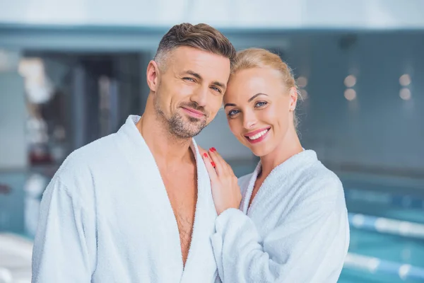 Fröhliches Paar im Bademäntel stehend und lächelnd — Stockfoto