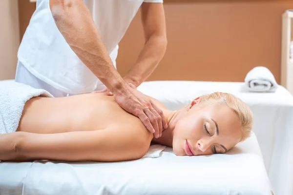 Mujer rubia disfrutando de masaje de terapeuta masculino en spa - foto de stock