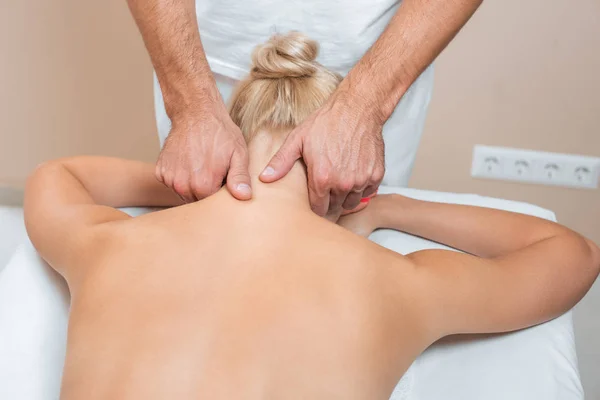 Masajista masculino haciendo masaje de cuello en salón de spa - foto de stock