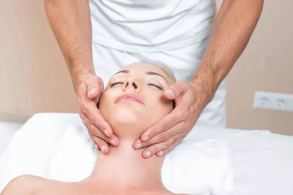 Hombre terapeuta haciendo masaje facial a la mujer en salón de belleza - foto de stock