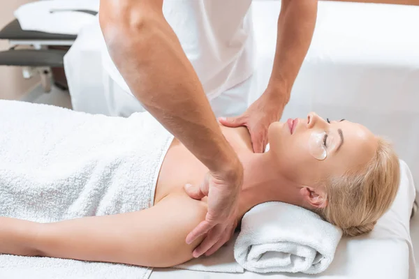 Masajista masculino haciendo masaje de hombro a mujer en salón de spa - foto de stock