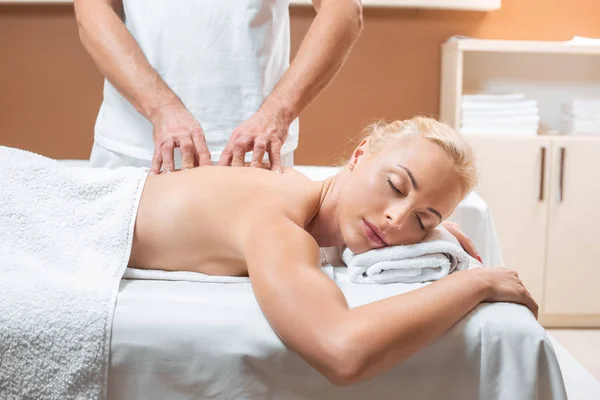 Mulher loira deitada com os olhos fechados, enquanto o homem fazendo massagem — Fotografia de Stock