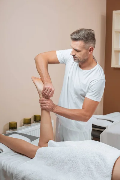 Guapo masajista haciendo relajante pies masaje - foto de stock