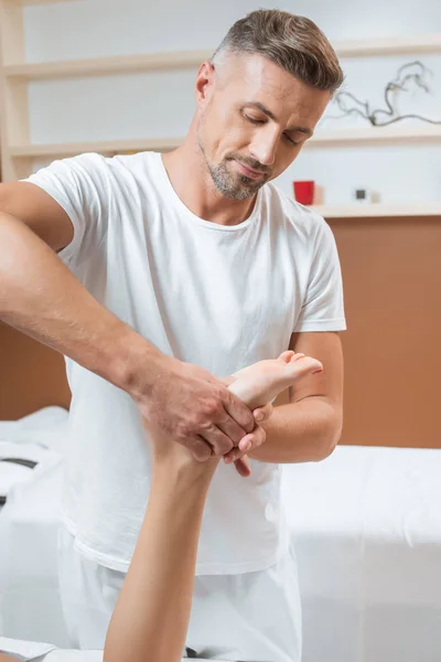 Adult handsome man massaging woman foot in spa — Stock Photo