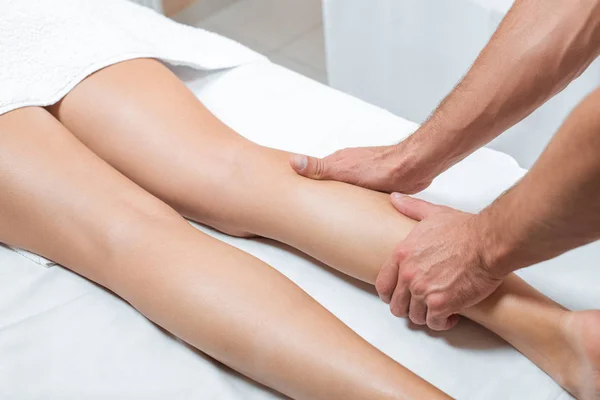 Cropped view of man massaging woman legs in spa center — Stock Photo