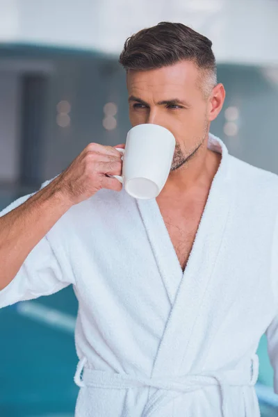 Homem bonito em roupão branco bebendo chá — Fotografia de Stock