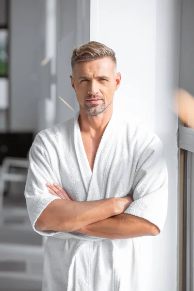 Handsome man in white bathrobe with arms crossed looking at camera — Stock Photo