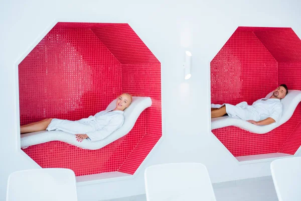 Доросла пара лежить на стільцях палуби в мозаїчних восьмикутниках у спа — стокове фото