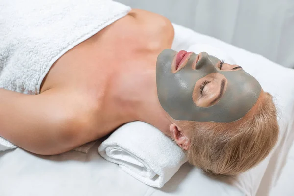 Primo piano di donna sdraiata con gli occhi chiusi e maschera di argilla facciale in spa — Foto stock