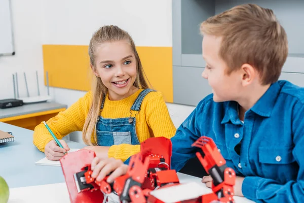 Compañeros de clase sonriendo y hablando durante la lección de robótica STEM - foto de stock