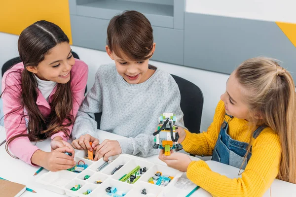 Happy classmates discussing ideas while making robot — Stock Photo