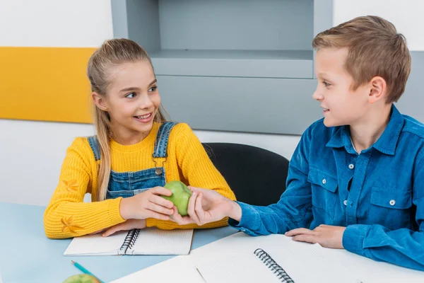 Compañeros de clase sonrientes después de compartir la lección manzana - foto de stock