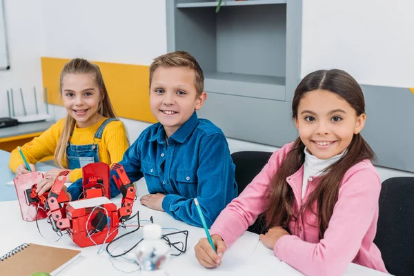 Glückliche Schüler basteln Roboter während der Robotikstunde — Stockfoto