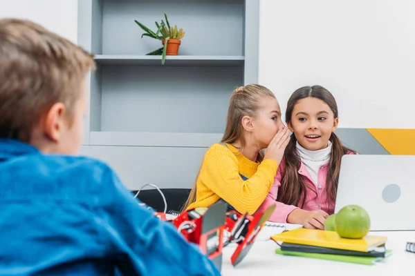 Happy classmates whispering and using laptop after lesson — Stock Photo