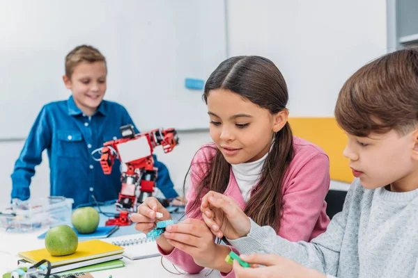 Счастливые одноклассники делают робота во время урока робототехники STEM — стоковое фото