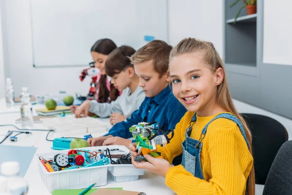 Fröhliche Klassenkameraden basteln während des Robotikkurses einen Roboter — Stockfoto