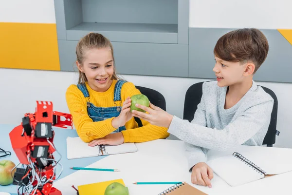 Happy classmates on break sharing apple — Stock Photo