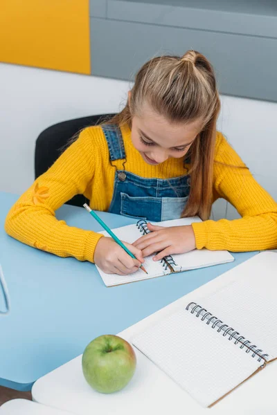 Шкільний малюк пише в блокноті під час занять — стокове фото
