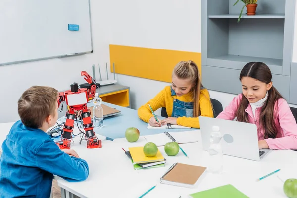 Escolares escrevendo e usando laptop na lição de robótica STEM — Fotografia de Stock