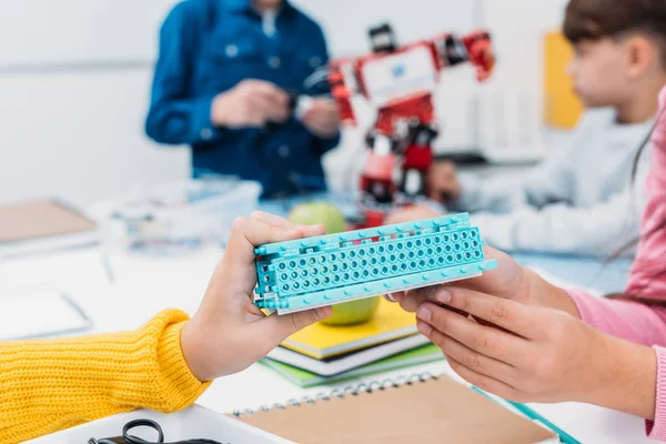 Cropped view of schoolkids holding robot part at STEM robotics lesson — Stock Photo