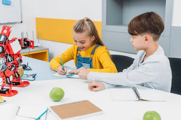 Les enfants écrivent dans des blocs-notes à la leçon de robotique STIM — Photo de stock