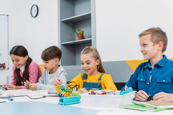 Attentive children working with parts of robot at STEM robotics lesson — Stock Photo