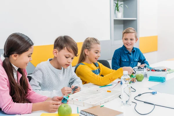 Schoolchildren putting a robot together during STEM robotics lesson — Stock Photo