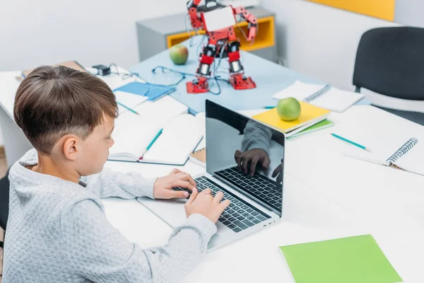 Scolaro digitando sulla tastiera del computer portatile alla scrivania in classe stelo — Foto stock