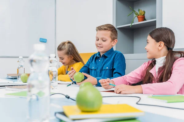 Happy children sitting at desk in classroom — Stock Photo