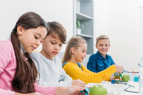 Konzentrierte Schüler sitzen am Schreibtisch und basteln Roboter in der Stammklasse — Stockfoto