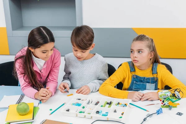 Escolares concentrados construindo robô com detalhes durante a aula STEM — Fotografia de Stock