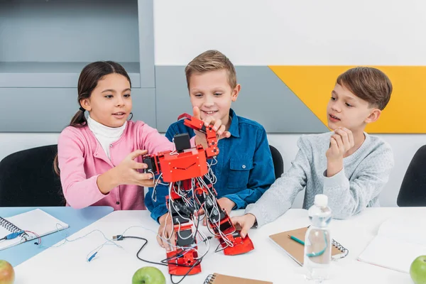 Smiling schoolchildren building red electric robot during STEM lesson — Stock Photo