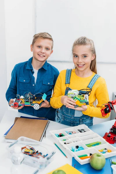 Smiling children holding electric robots in stem education class — Stock Photo