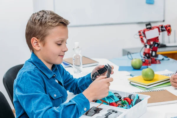 Cute schoolboy making mechanical robot with details in stem class — Stock Photo