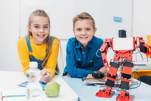 Schoolboy and schoolgirl looking at camera and smiling in stem education class — Stock Photo