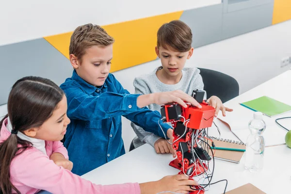 Schoolchildren touching red electric robot in stem class — Stock Photo