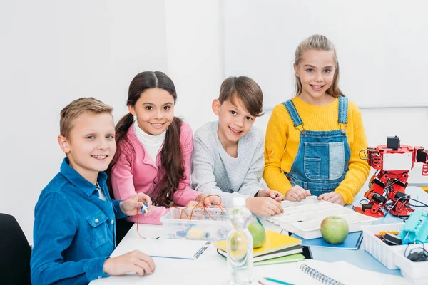 Schoolchildren looking at camera and smiling at desk in stem education class — Stock Photo