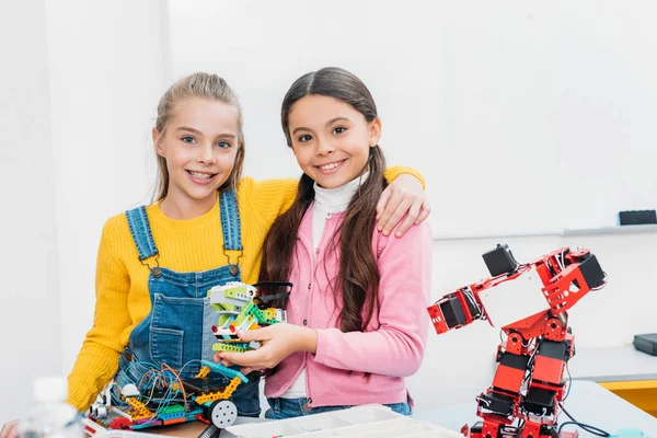 Colegialas sonrientes sosteniendo robot y mirando a la cámara en la clase de tallo - foto de stock