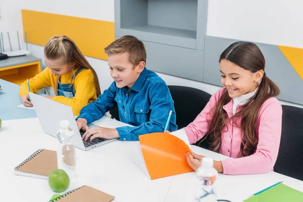 Glückliche Schulkinder am Schreibtisch in der Stammklasse — Stockfoto