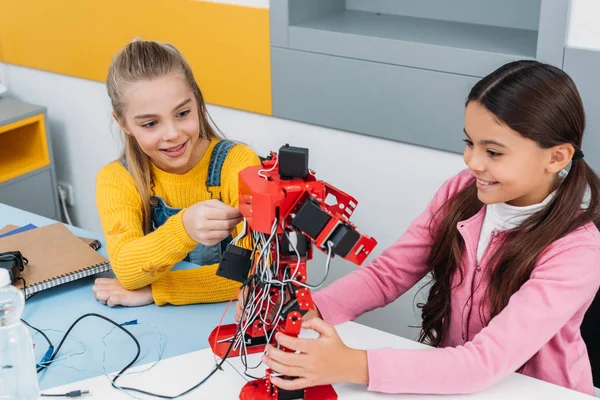 Sonrientes colegialas tocando robot rojo hecho a mano en clase de tallo - foto de stock