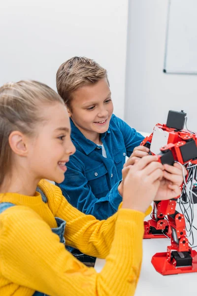 Lächelnde Schulkinder programmieren gemeinsam Roboter im Unterricht — Stockfoto