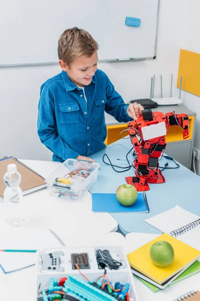 Happy schoolboy working on handmade robot model during STEM lesson — Stock Photo