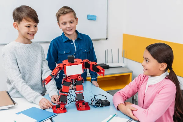 Happy schoolchildren programming robot together during STEM educational class — Stock Photo