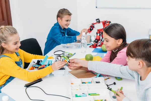 Niños sonrientes trabajando juntos en el proyecto STEM en clase - foto de stock