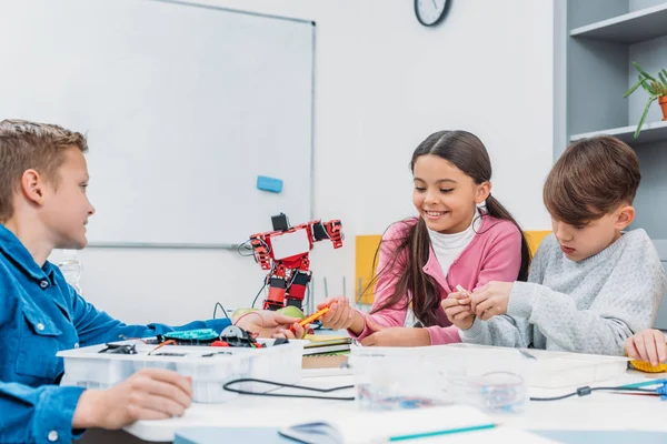 Compagni di classe seduti a tavola, che parlano e lavorano insieme sul progetto durante la lezione STEM — Foto stock