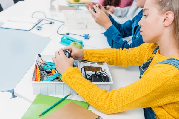 Schoolgirl sitting at table and working together with classmates on STEM project in classrom — Stock Photo