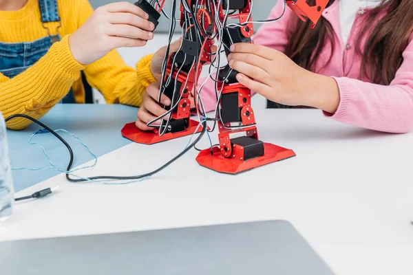 Vue recadrée de camarades de classe travaillant ensemble sur le modèle robot pendant la leçon de STIM — Photo de stock