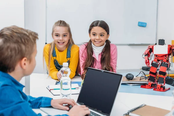 Niños escolares que programan robots juntos y usan computadoras portátiles durante la clase educativa STEM - foto de stock